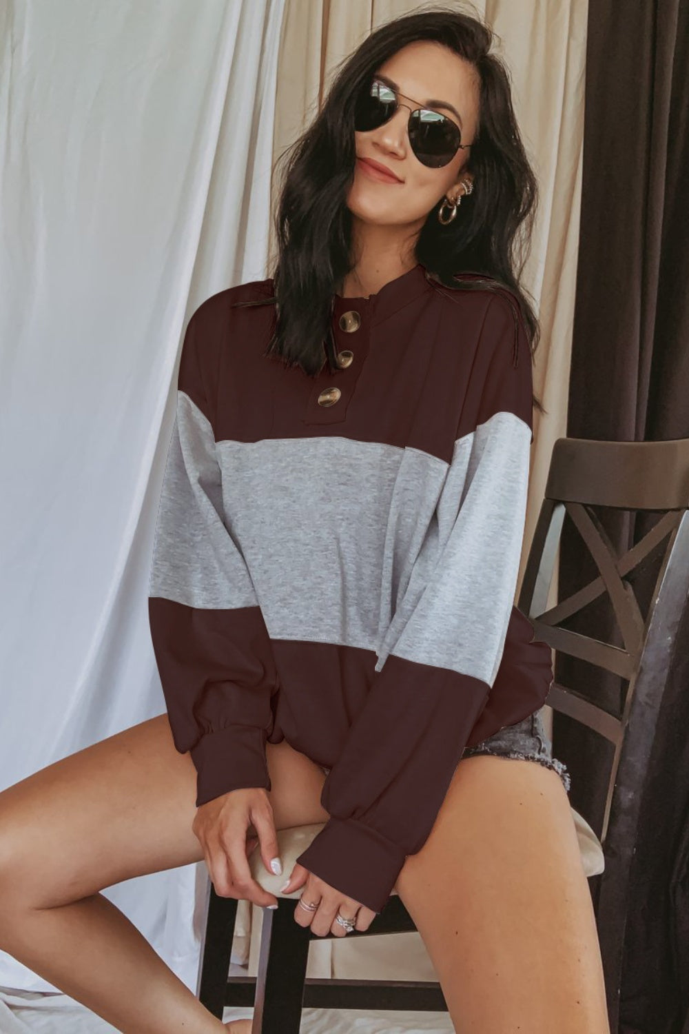 A person wearing a long-sleeved, round neck sweatshirt with a striped pattern in different shades of brown and gray.