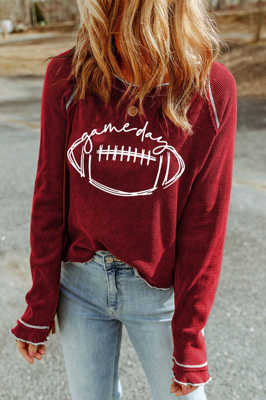 A person wearing a red round neck long sleeve football sweatshirt with a graphic of a football in the center.